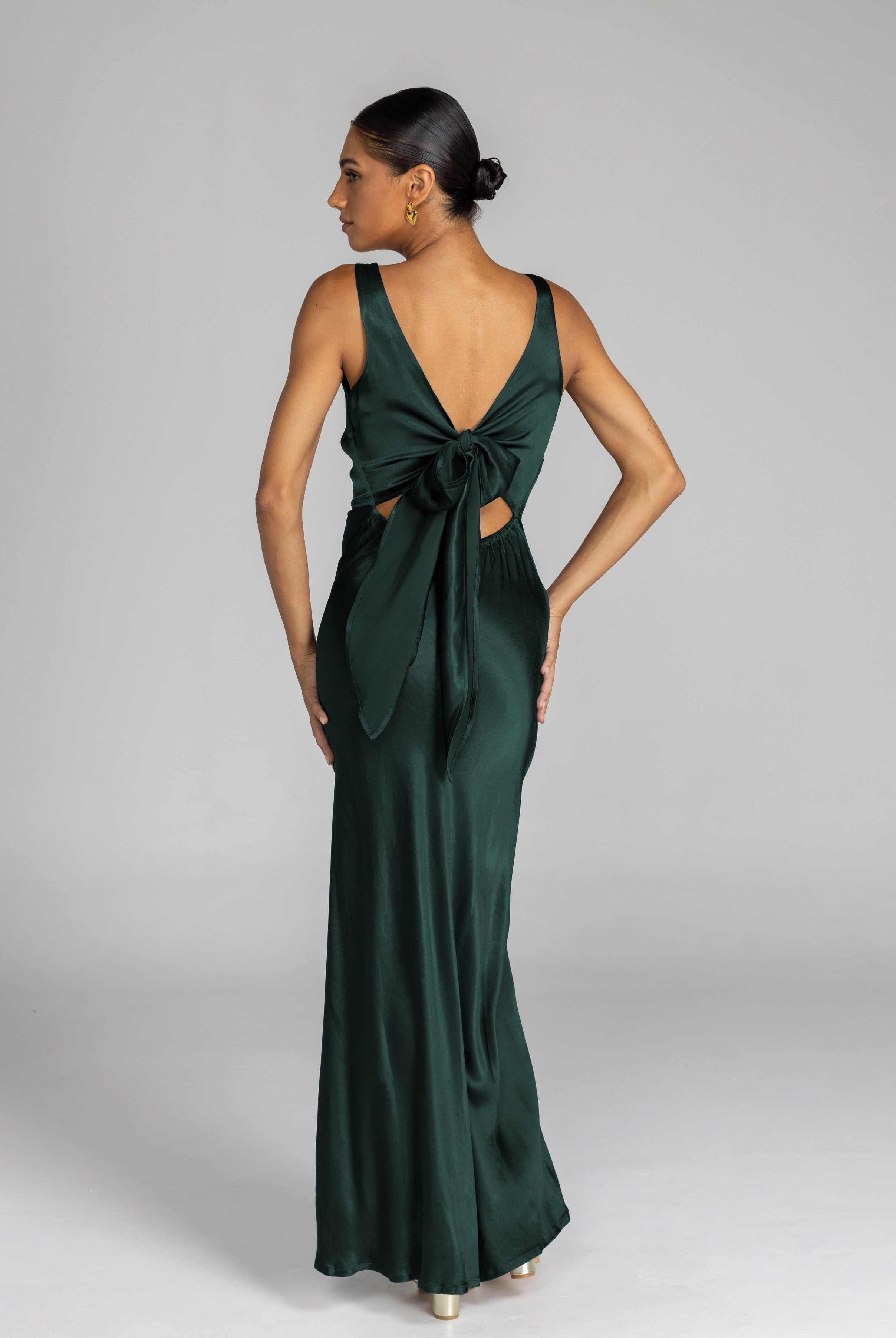 Woman wearing a green evening gown with a bow detail on a gray background