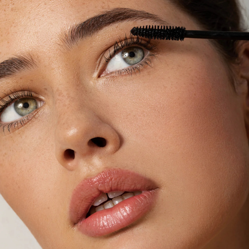 Close-up of a woman applying mascara to her eyelashes.