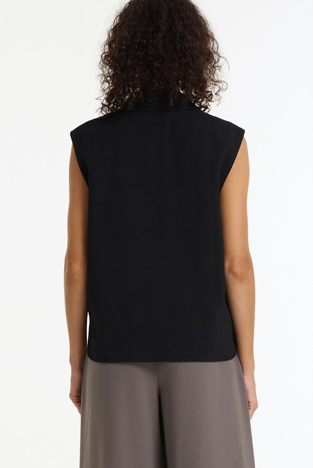 Person wearing Forevermore Tailored Vest black sleeveless blazer by BLAK and gray pants on a white background