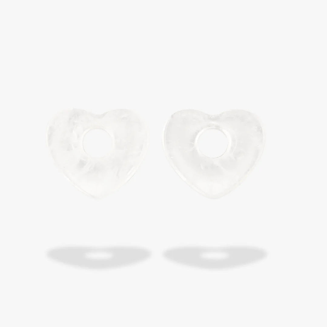 A pair of clear quartz heart-shaped charms, displayed on a clean white background with soft shadows below.