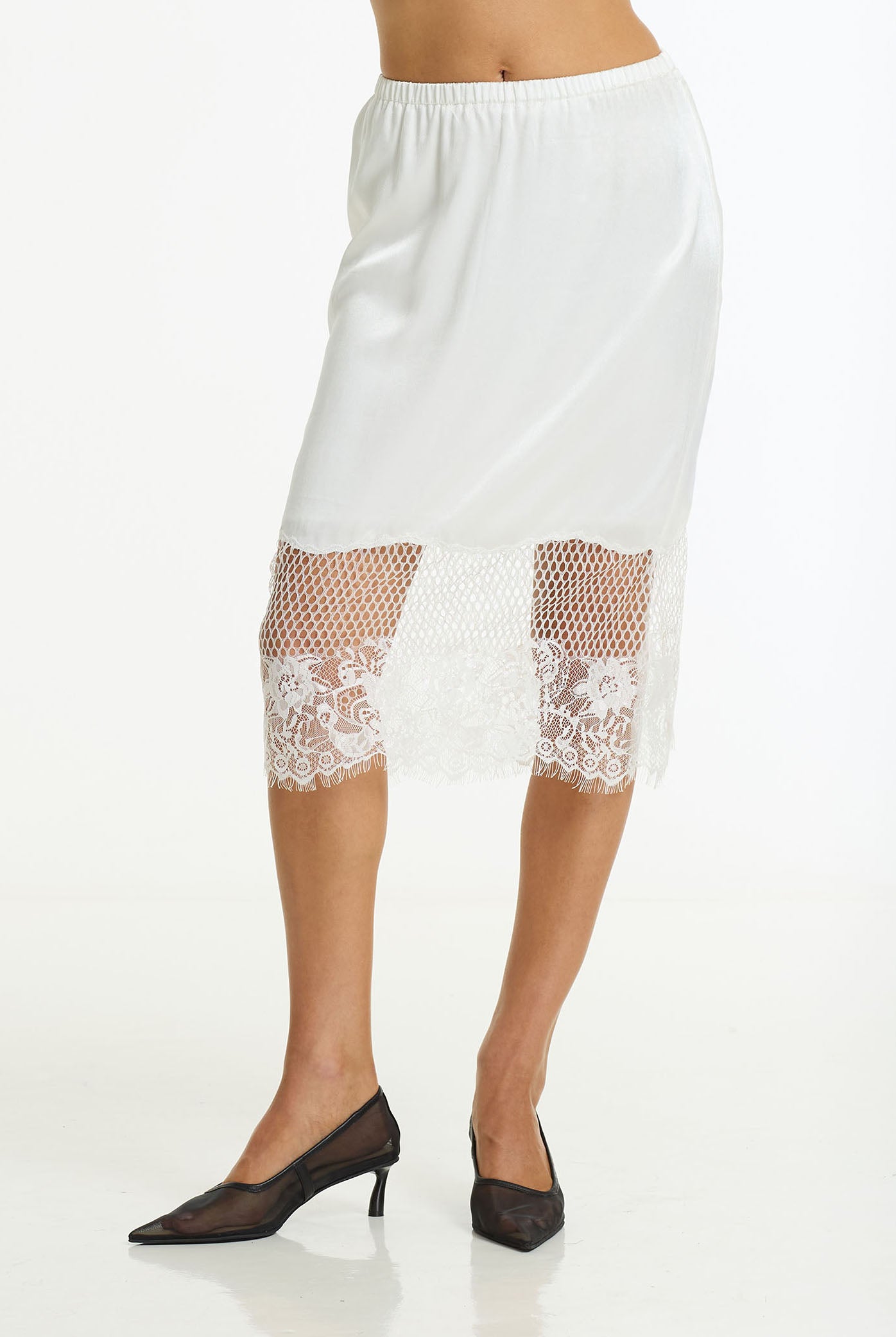 Parisian Girl Satin Lace Skirt in ivory by BLAK, shown on a model wearing black pointed-toe heels against a white studio background.