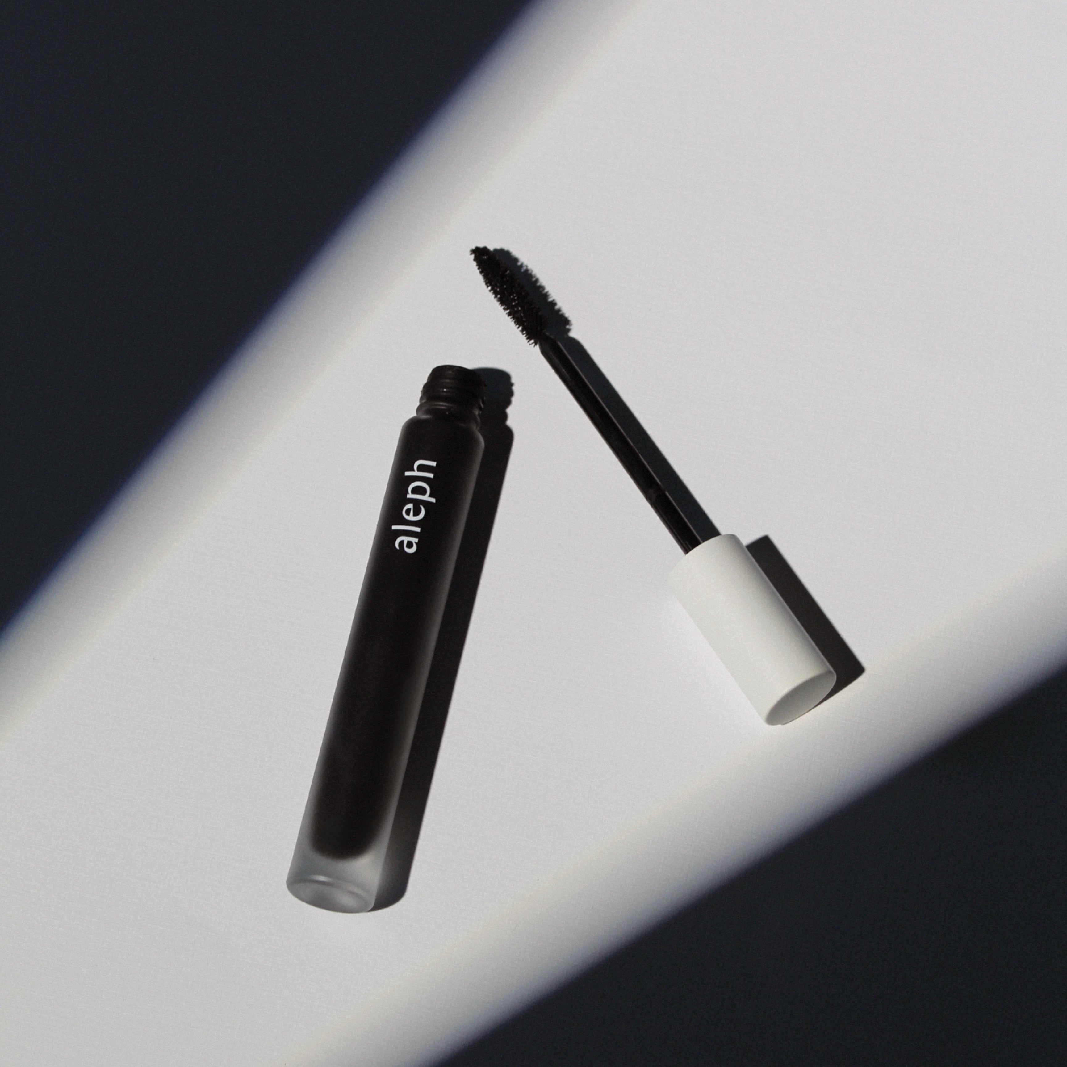 Mascara with a white cap on a reflective surface