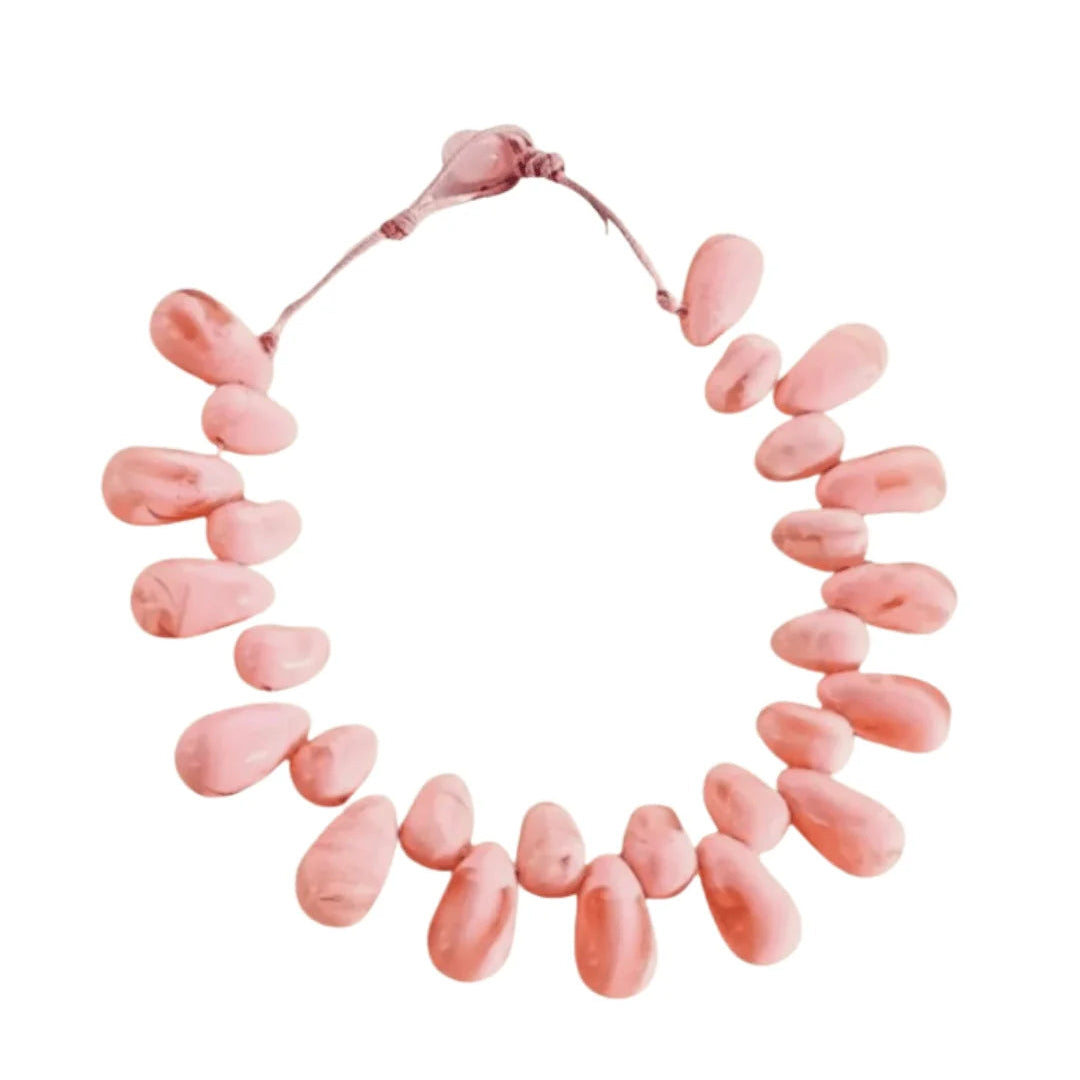 A Rhodin necklace made of irregular, teardrop-shaped pink beads arranged in a circle on a white background.