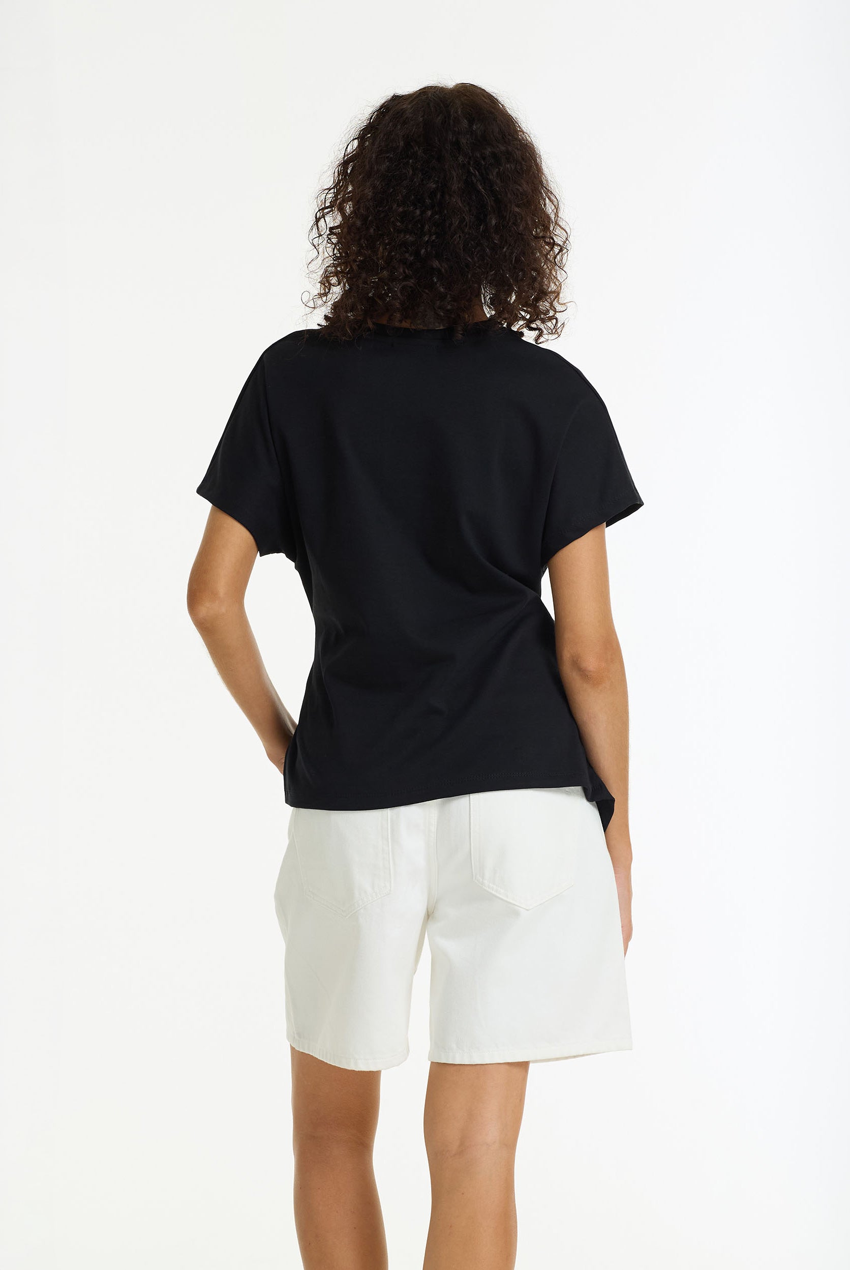 Person wearing a black t-shirt and white shorts on a white background