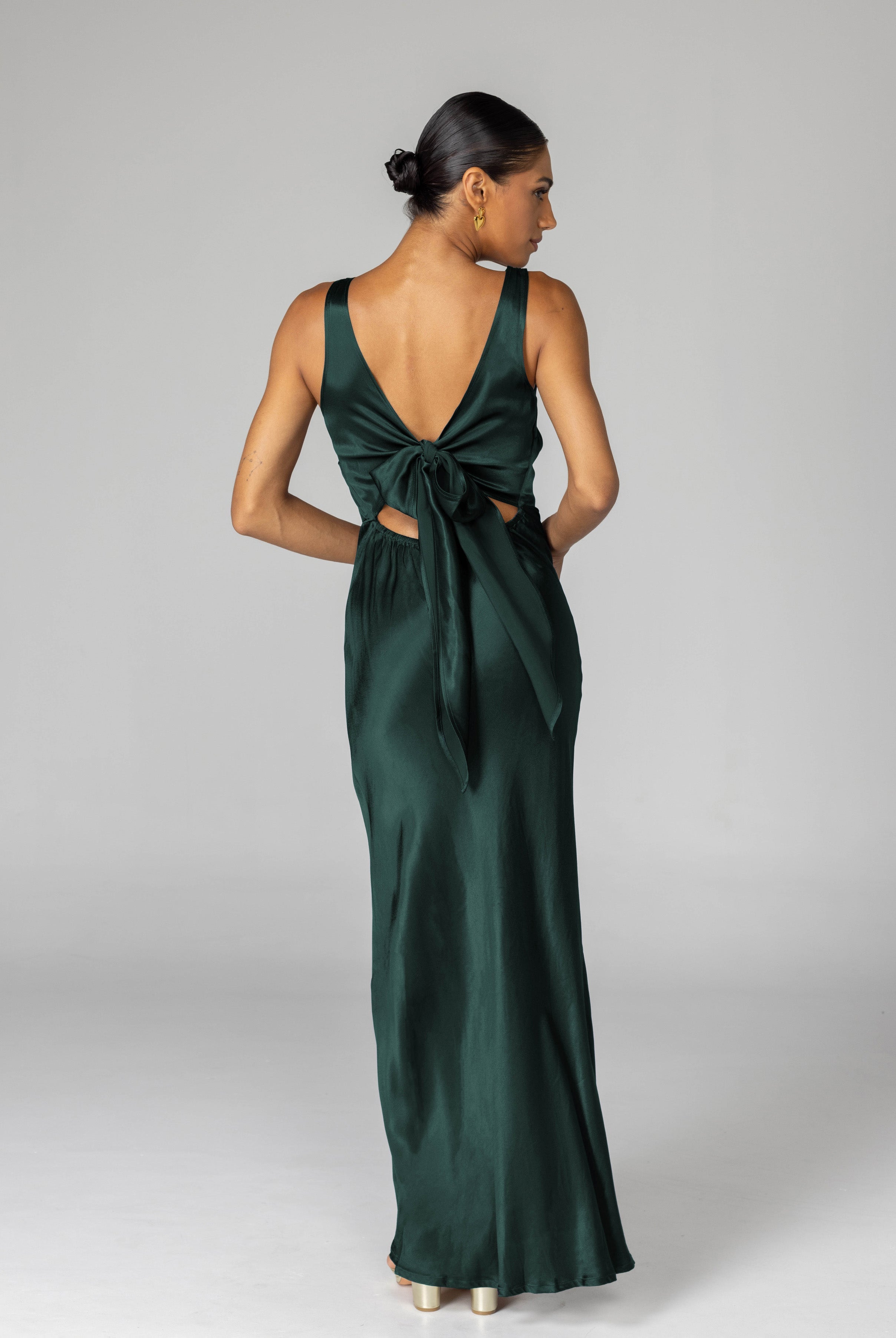 Woman wearing a green evening gown with cut-out design on a gray background