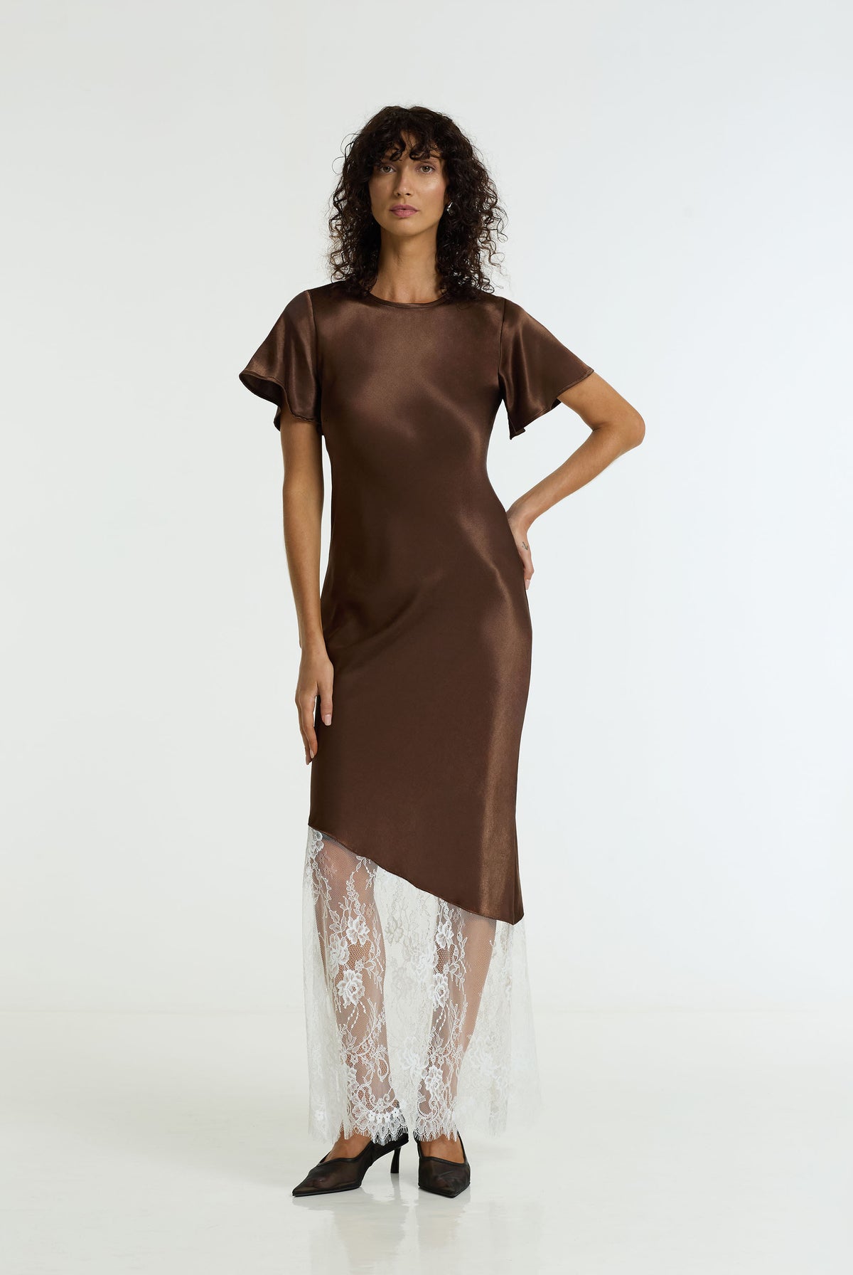 A woman modeling the After Dark Satin Lace Maxi Dress in chocolate by BLAK, against a plain white studio background.