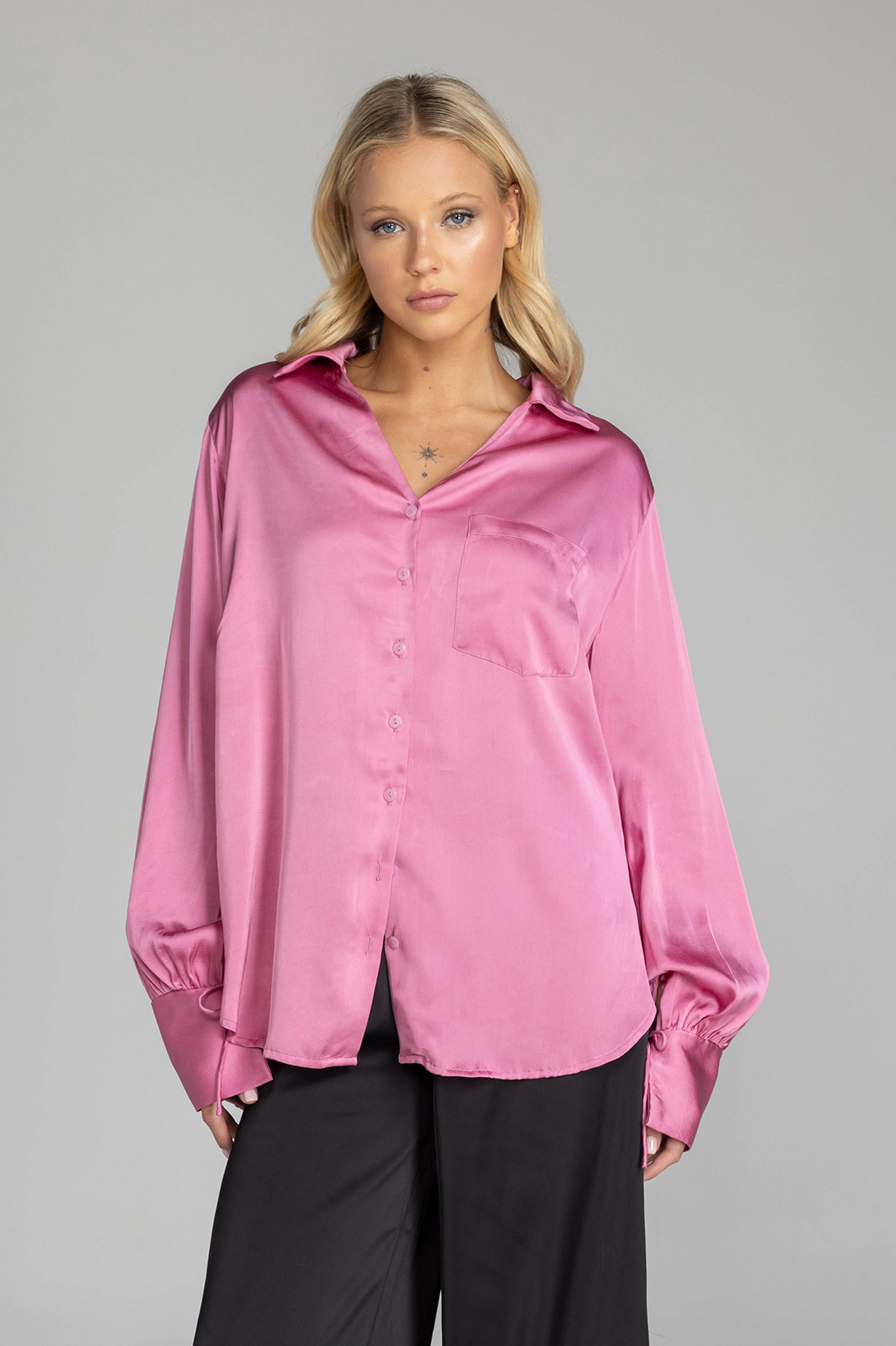 Woman wearing a pink satin shirt against a gray background