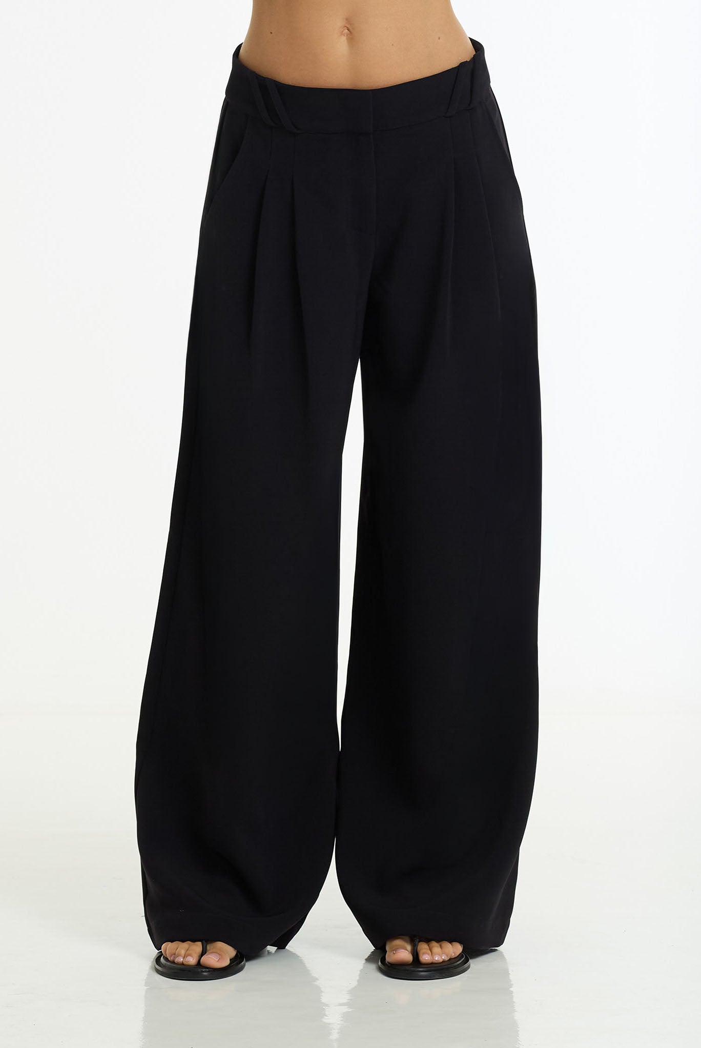 Dante Wide Leg Pant in black by BLAK, shown on a model wearing black slide sandals against a white studio background.