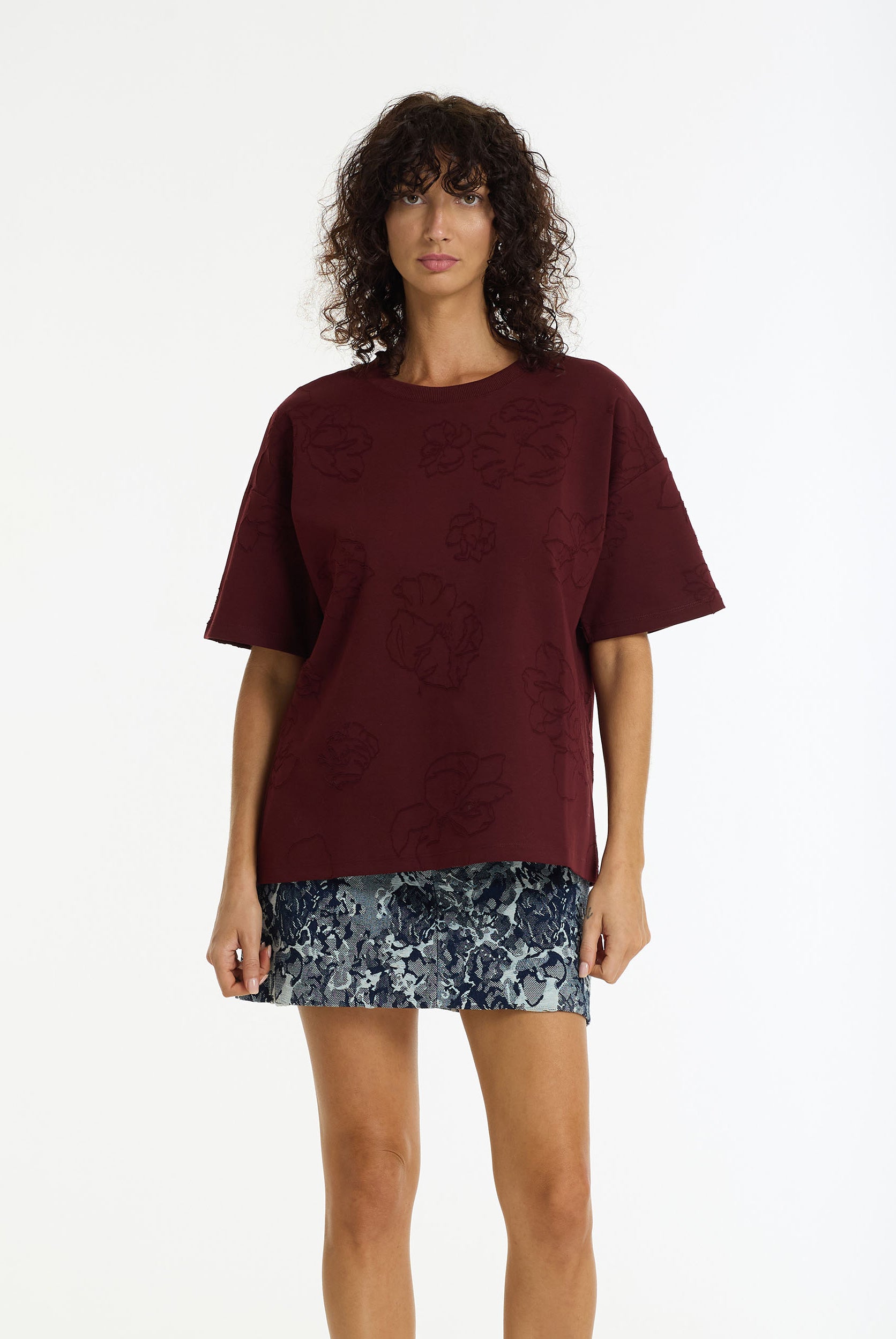 Woman wearing the Off Duty Flora Textured Tee in burgundy by BLAK and blue floral mini on a white background