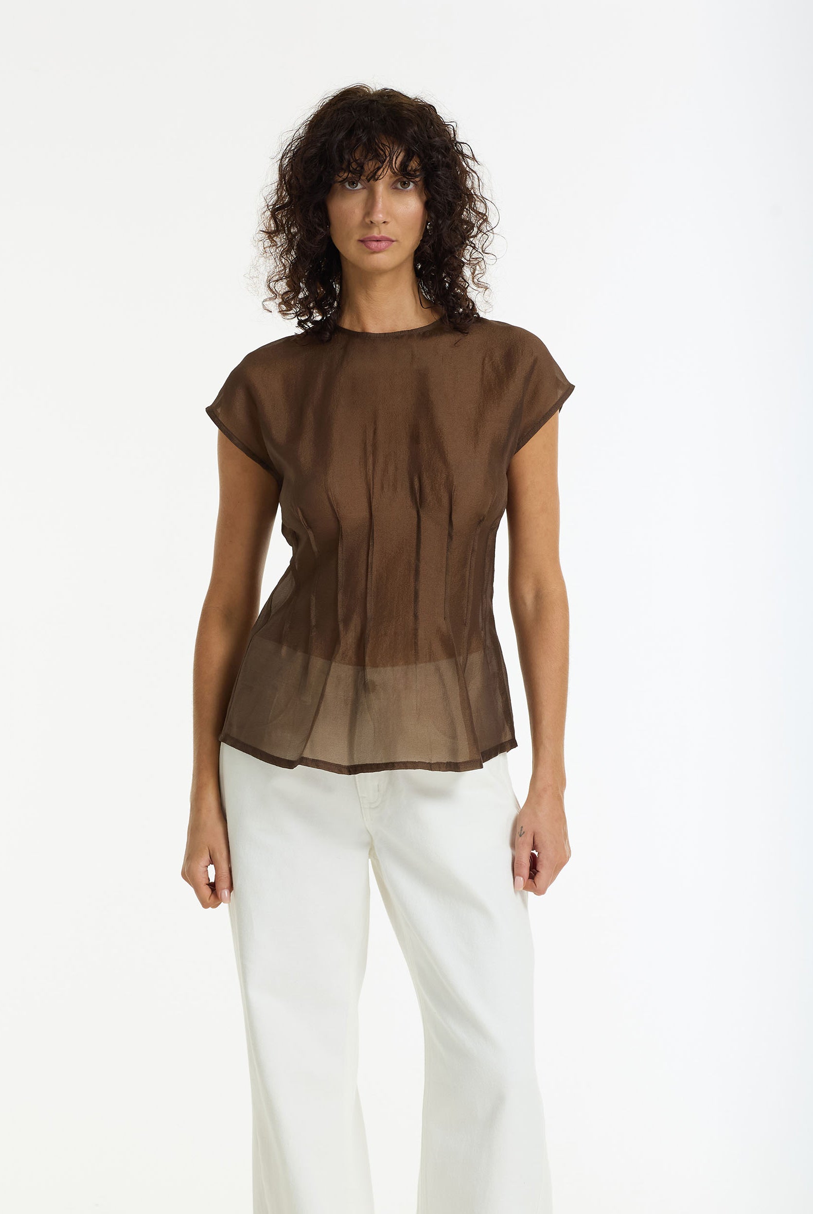 Woman wearing Refined Romance Sheer Pintuck Top in chocolate by BLAK and white jeans on a white background